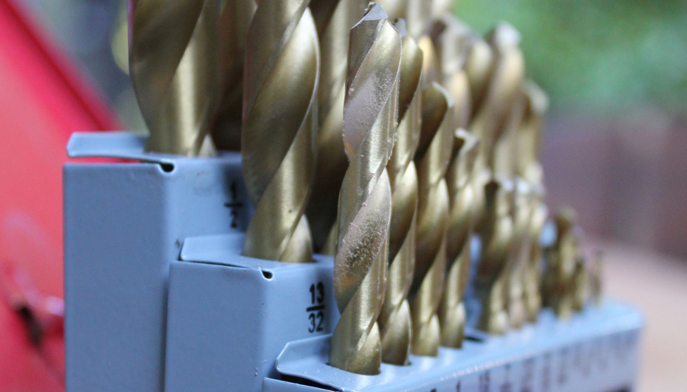 Set of titanium-coated HSS twist drill bits arranged by size in a stepped metal index case