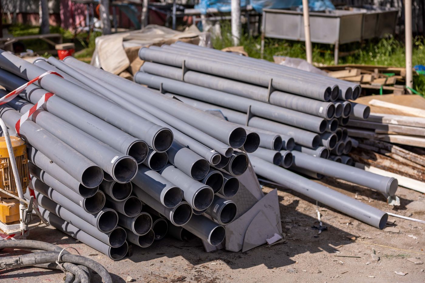 Stacks of grey plastic water pipes of several diameters laid out at a construction site