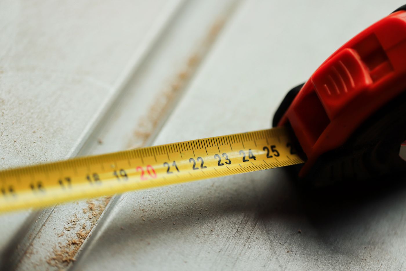 Close-up of a steel tape measure with metric markings extended across a construction surface
